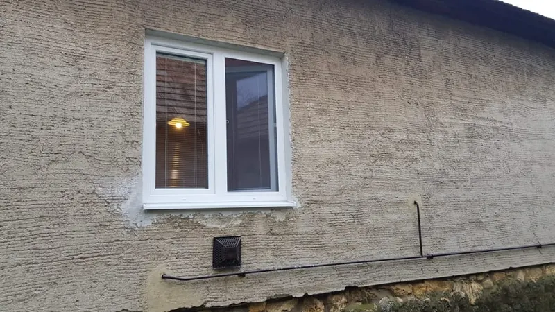 Staré okno v&nbsp;omietnutej fasáde rodinného domu